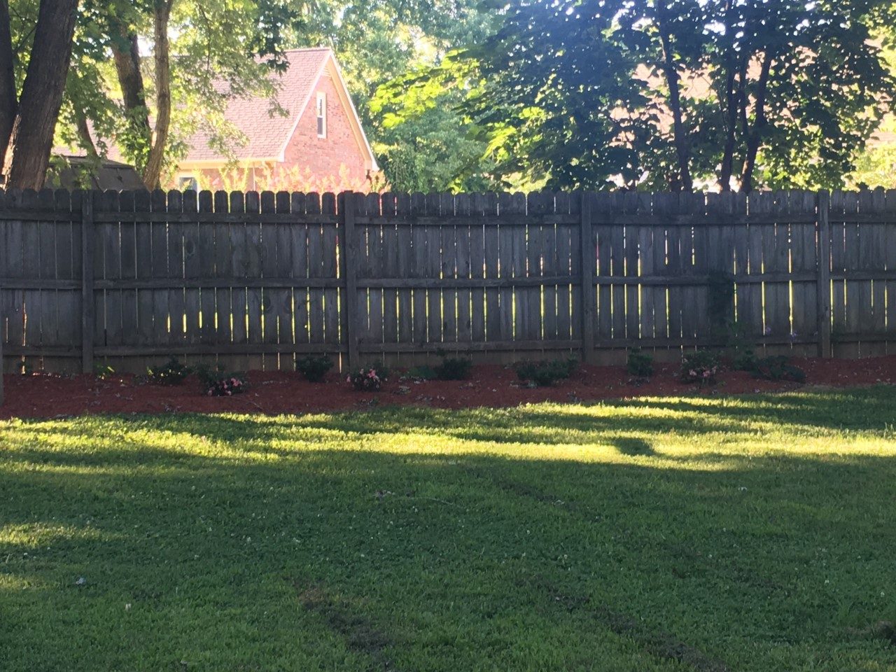 Mulched bed along a wooden fence after Turf Envy work